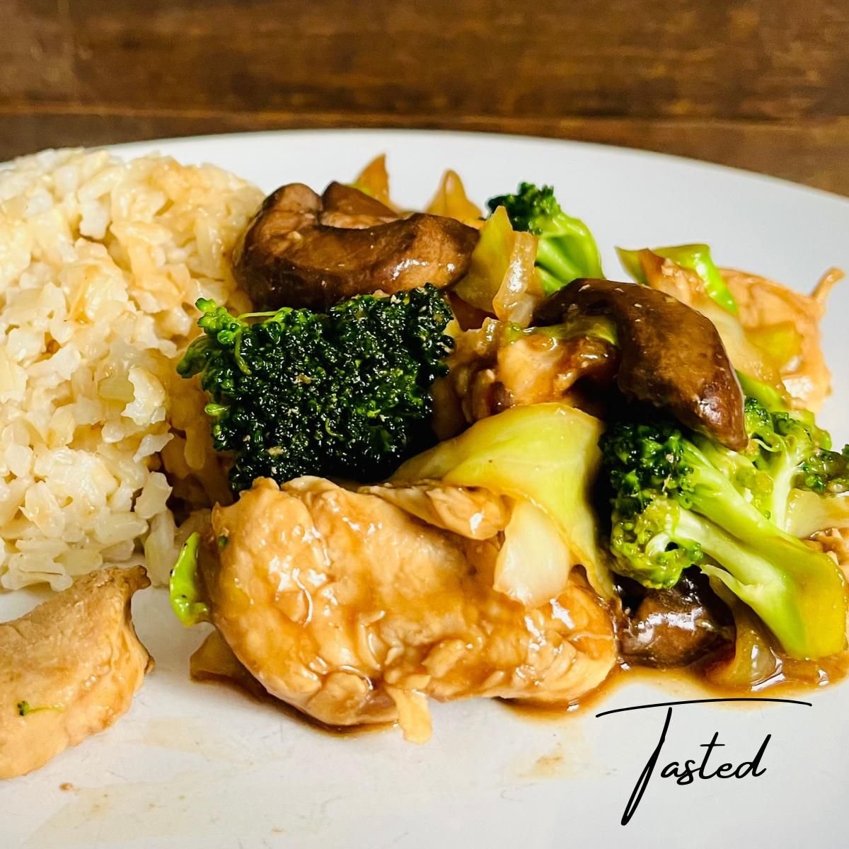 Chicken, broccoli and mushroom stir fry with brown rice on a white plate