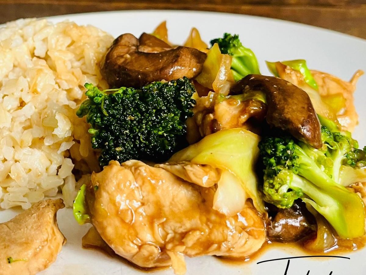 Chicken, broccoli and mushroom stir fry with brown rice on a white plate
