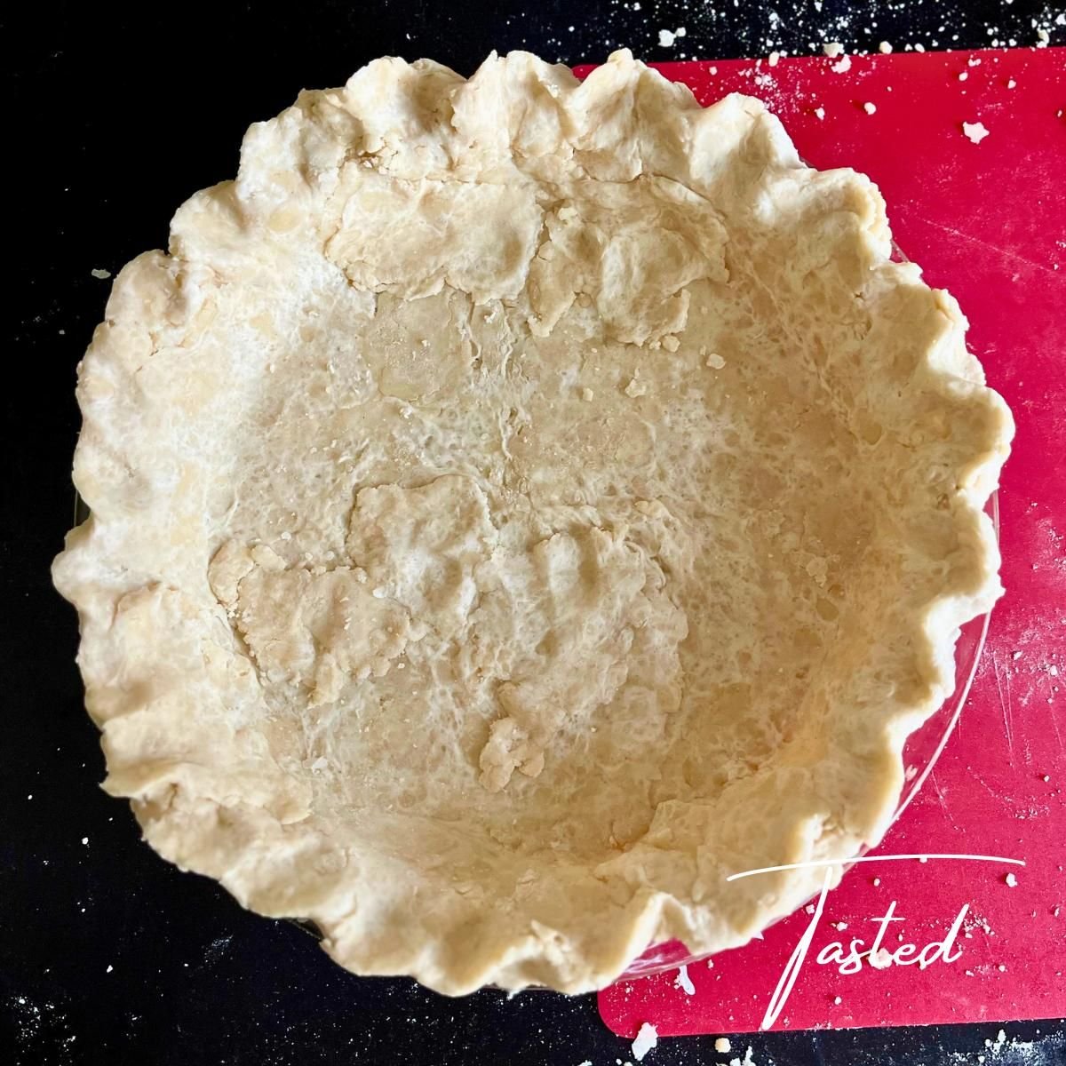 Unbaked coconut oil pie crust with fluted edges in a glass pie dish