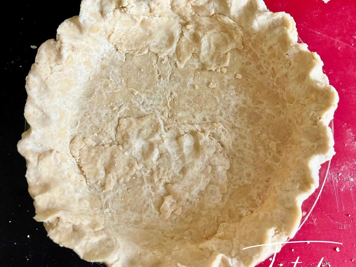 Unbaked coconut oil pie crust with fluted edges in a glass pie dish