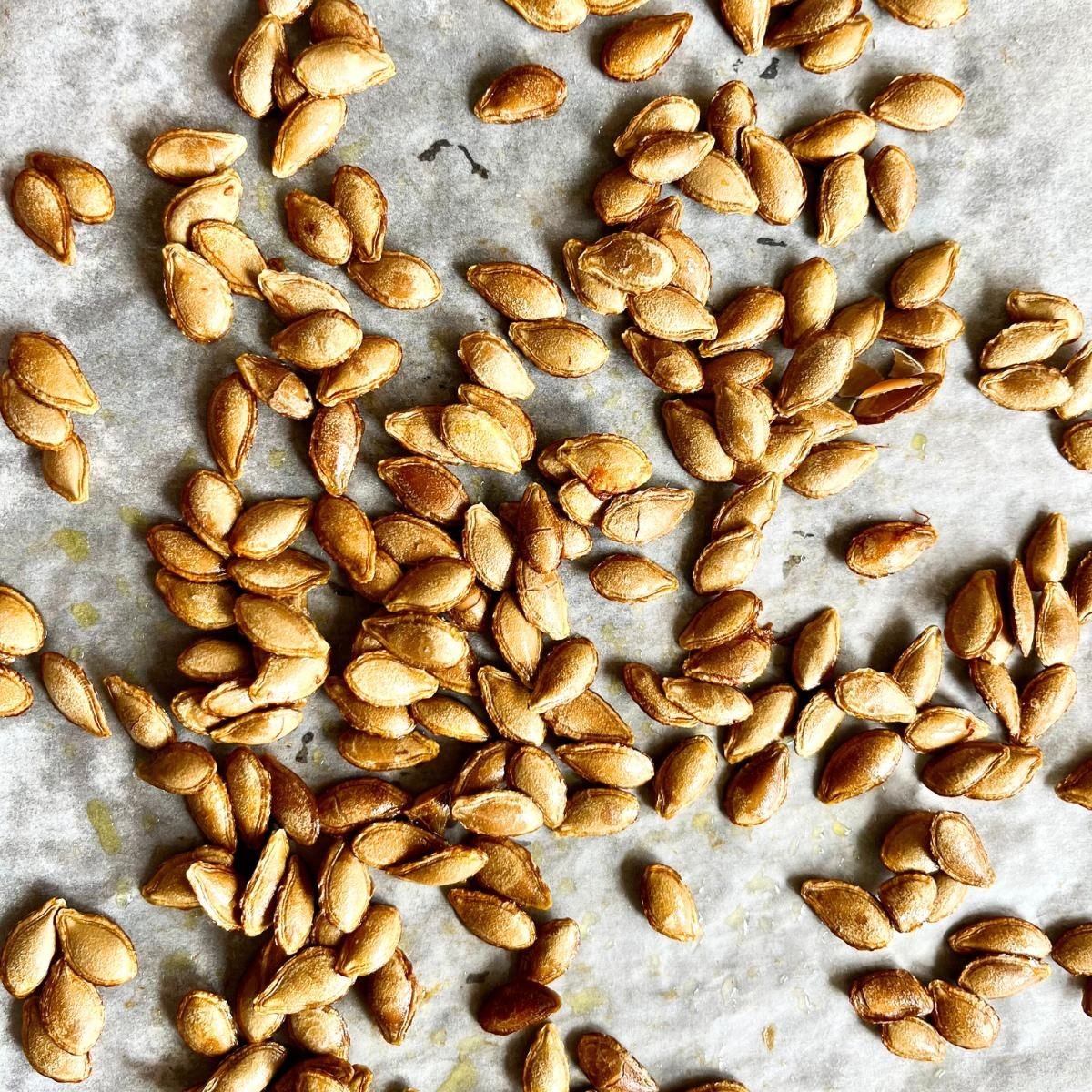 Crispy roasted pumpkin seeds spread out on parchment paper