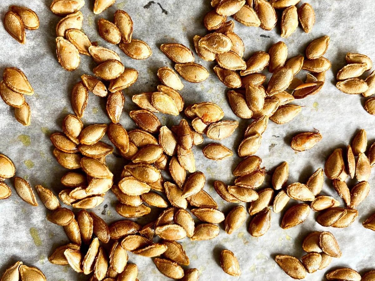 Crispy roasted pumpkin seeds spread out on parchment paper